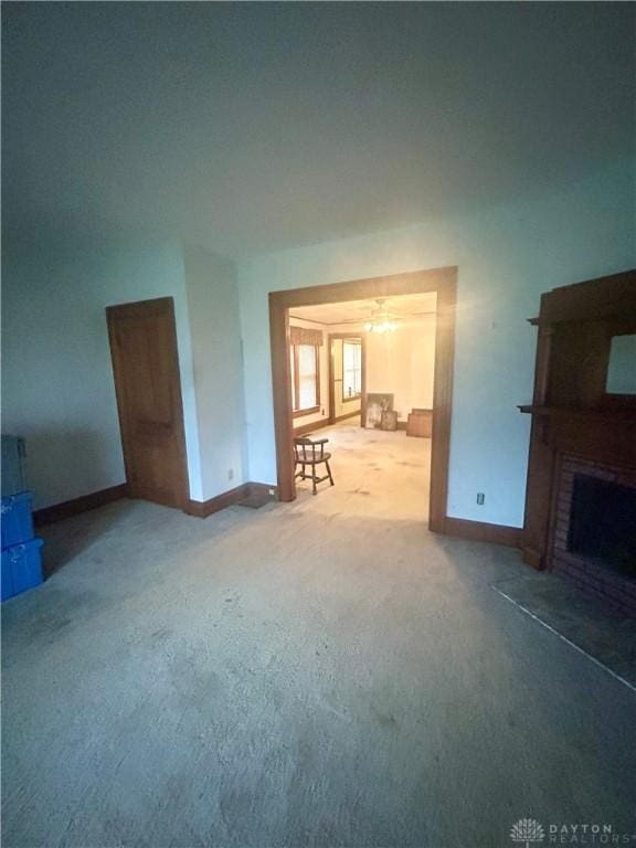 unfurnished living room with carpet, a fireplace, and ceiling fan