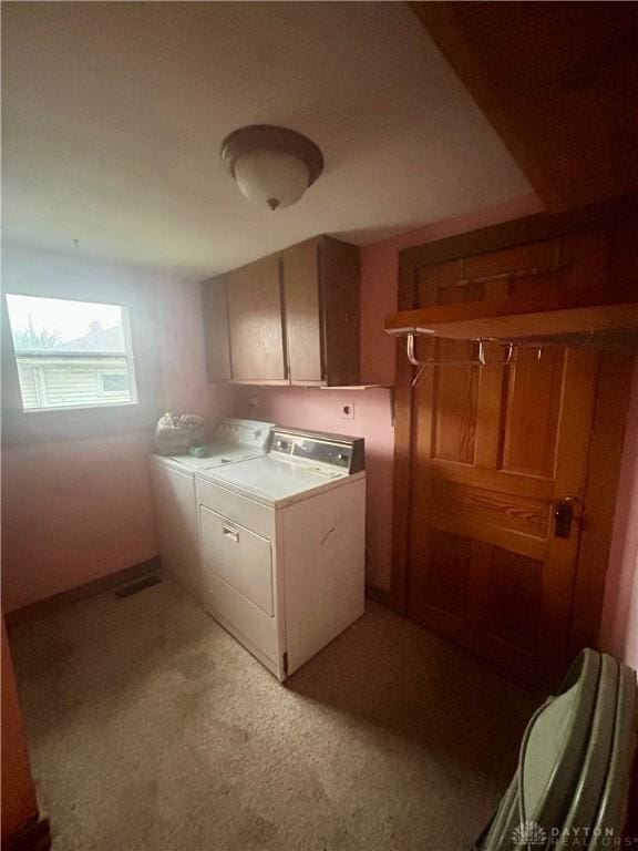 laundry room featuring cabinets, independent washer and dryer, and light carpet