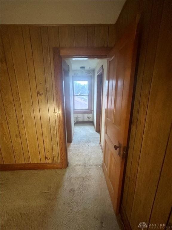 hallway featuring wood walls and light colored carpet