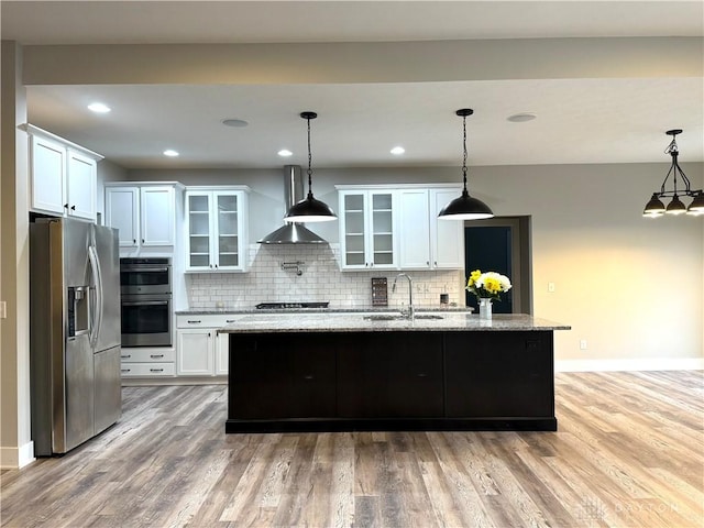 kitchen featuring appliances with stainless steel finishes, sink, pendant lighting, white cabinets, and an island with sink