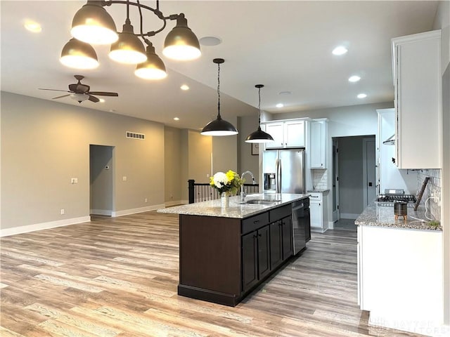 kitchen featuring stainless steel appliances, a kitchen island with sink, sink, decorative light fixtures, and white cabinets