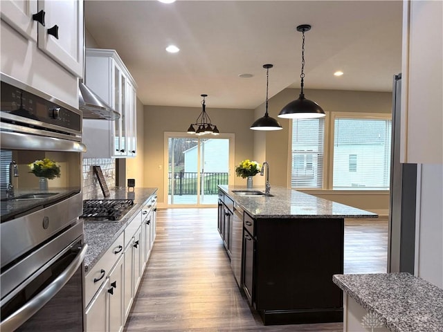 kitchen featuring a center island with sink, white cabinets, hardwood / wood-style floors, and sink