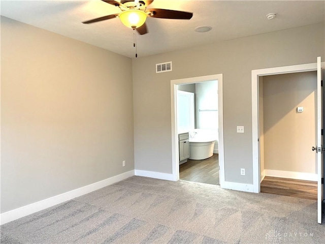 unfurnished bedroom featuring ensuite bath, ceiling fan, and light carpet