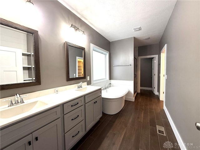 bathroom featuring a bathing tub, hardwood / wood-style floors, vanity, and a textured ceiling