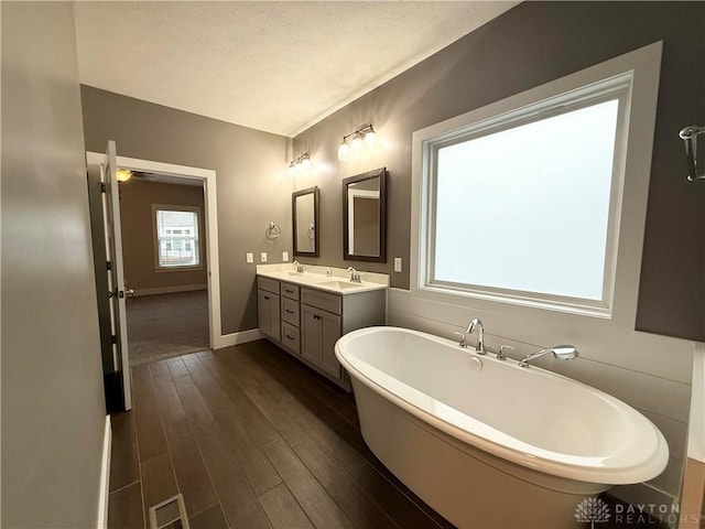 bathroom with hardwood / wood-style flooring, a bathtub, vanity, and a wealth of natural light