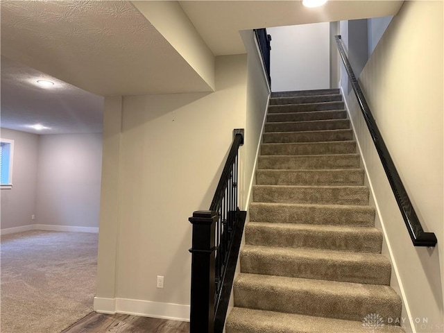 stairway featuring a textured ceiling and hardwood / wood-style flooring