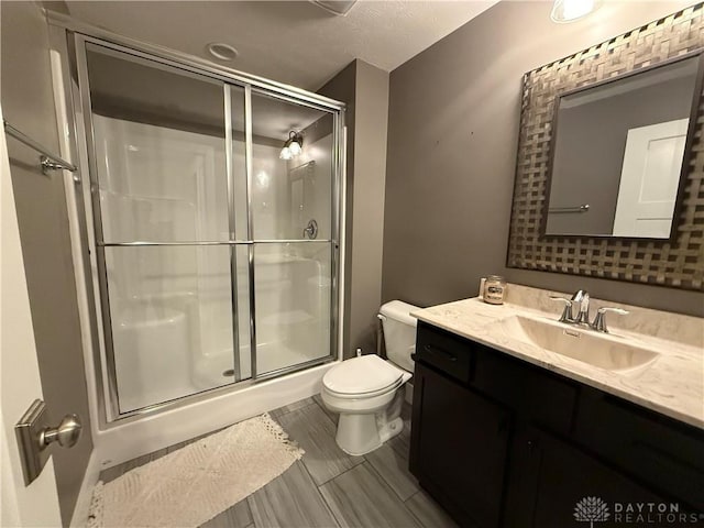 bathroom with vanity, toilet, and a shower with shower door