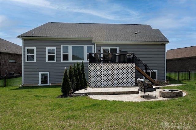 back of house with a fire pit, a deck, and a lawn