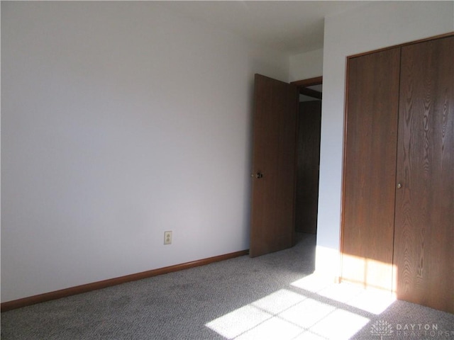 unfurnished bedroom with light colored carpet and a closet