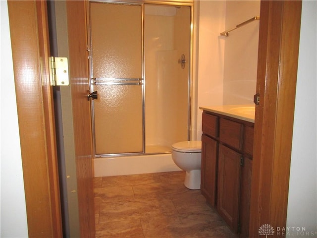 bathroom featuring tile patterned flooring, vanity, toilet, and an enclosed shower