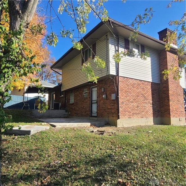 rear view of property featuring a yard and a patio area