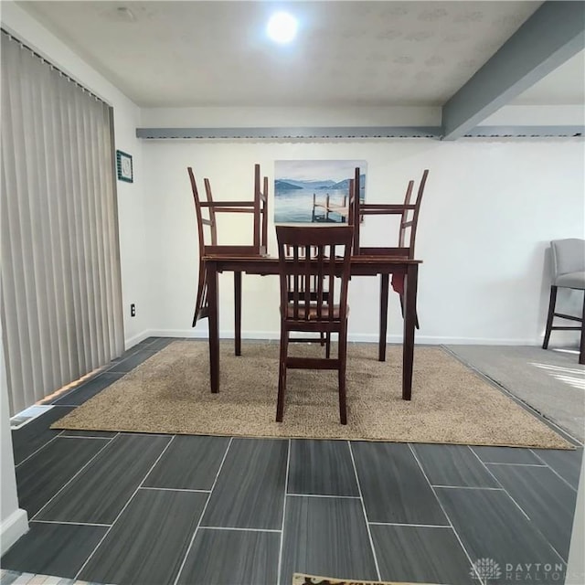 dining space featuring beamed ceiling