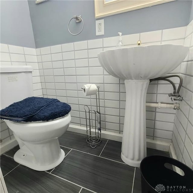 bathroom with tile walls and toilet