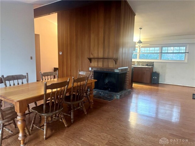 dining space with a brick fireplace and wood finished floors
