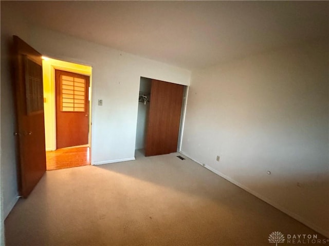 unfurnished bedroom featuring light carpet, a closet, and visible vents