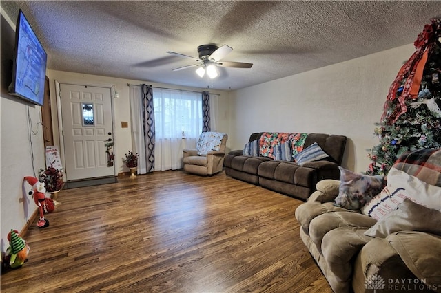 living room featuring ceiling fan, dark wood-type flooring, and a textured ceiling