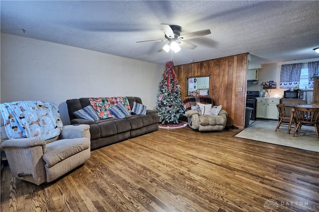 living room with ceiling fan, a textured ceiling, and hardwood / wood-style flooring