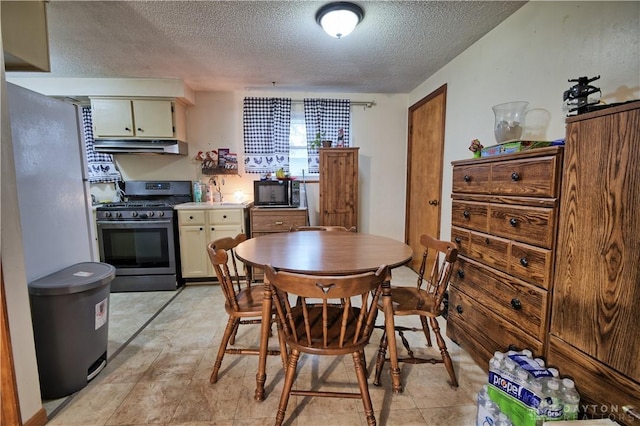 kitchen with cream cabinets, a textured ceiling, and stainless steel range with gas stovetop