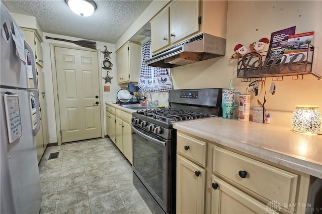 kitchen with sink, black gas range, a textured ceiling, and cream cabinets