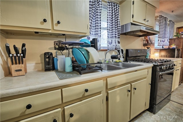 kitchen with sink, black gas range oven, and cream cabinets