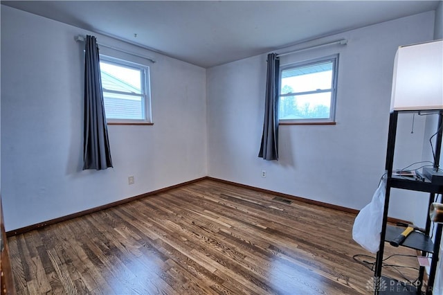 unfurnished room with plenty of natural light and dark wood-type flooring