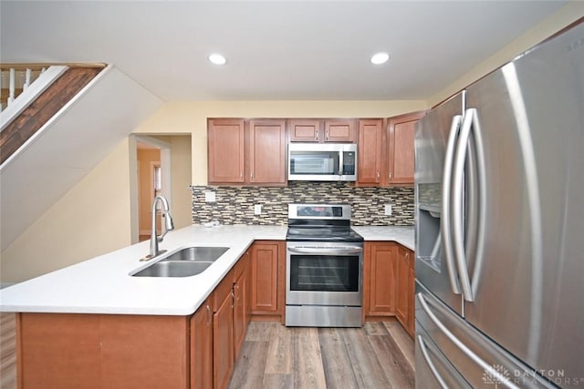 kitchen featuring sink, light hardwood / wood-style flooring, decorative backsplash, kitchen peninsula, and stainless steel appliances