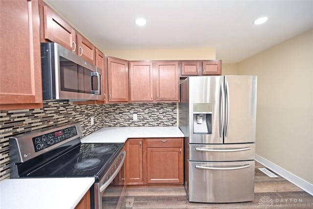 kitchen with backsplash, stainless steel appliances, and hardwood / wood-style flooring