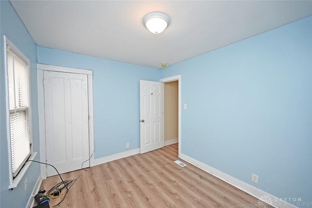 unfurnished bedroom with light wood-type flooring and a closet