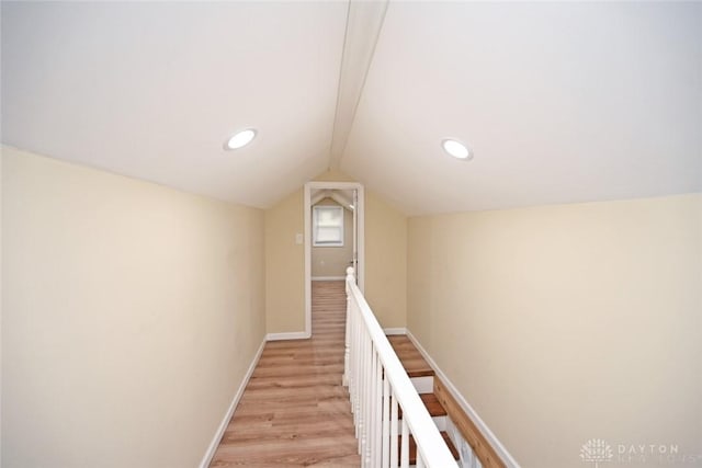 hallway with light hardwood / wood-style flooring and lofted ceiling with beams