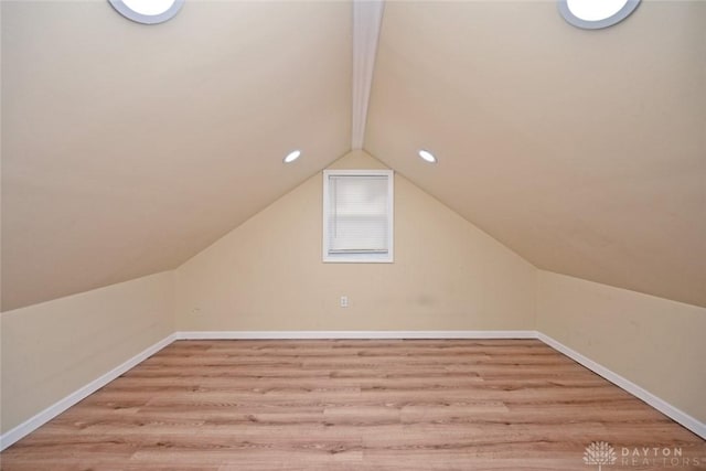 additional living space with vaulted ceiling with beams and light wood-type flooring