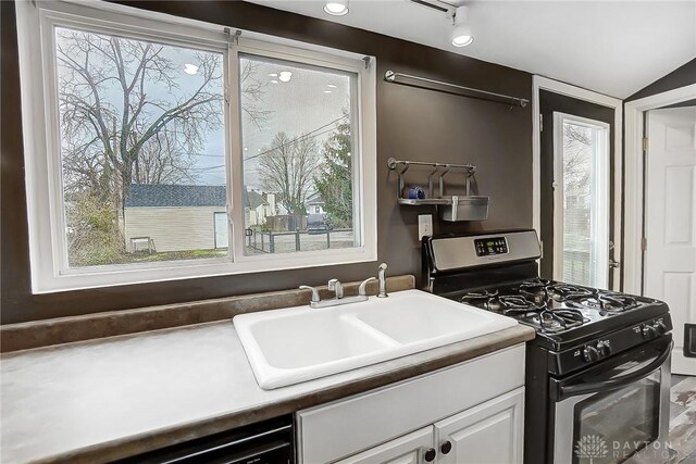 kitchen with white cabinets, stainless steel gas range oven, a healthy amount of sunlight, and sink