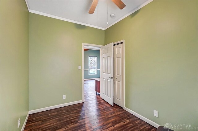 empty room with ceiling fan, crown molding, and dark wood-type flooring