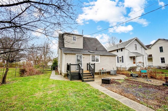 back of property featuring central air condition unit and a yard