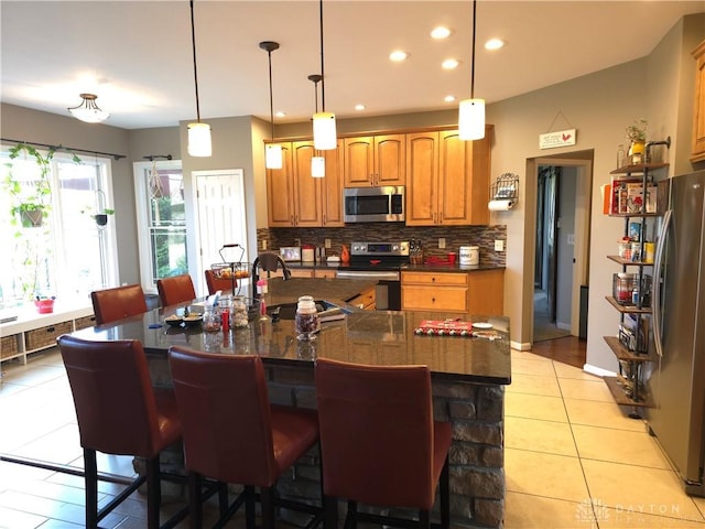 kitchen with sink, decorative backsplash, light tile patterned floors, a kitchen bar, and stainless steel appliances