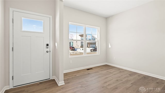 foyer entrance featuring baseboards, visible vents, and light wood finished floors