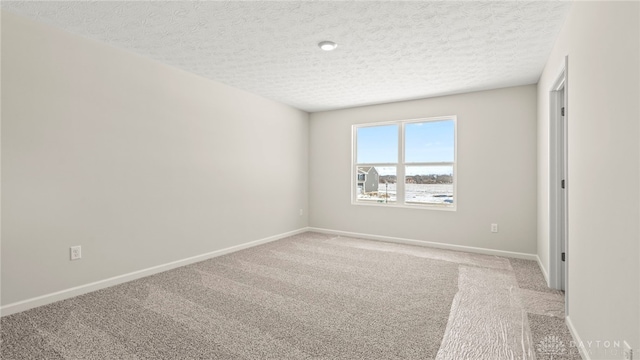 empty room featuring baseboards, a textured ceiling, and light colored carpet