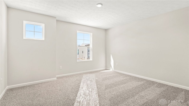 unfurnished room with carpet, a textured ceiling, and baseboards