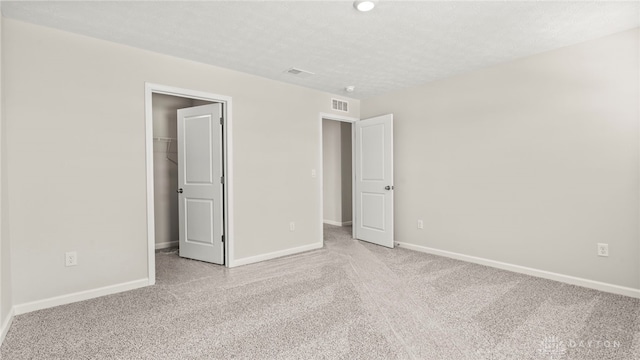 unfurnished bedroom with visible vents, light colored carpet, a spacious closet, and baseboards