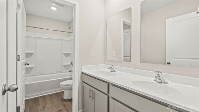 bathroom with visible vents, a sink, shower / bathing tub combination, and wood finished floors