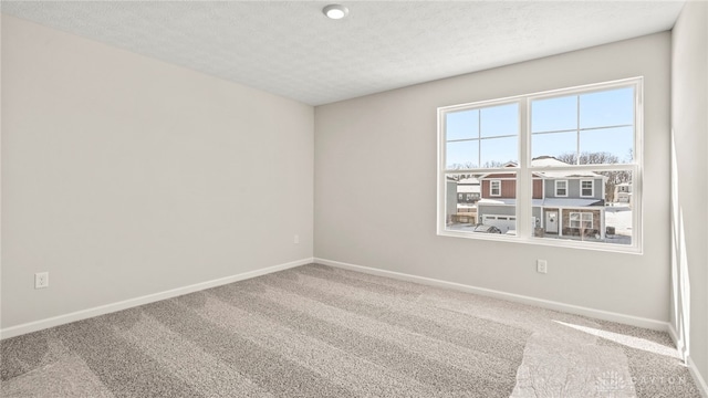 carpeted spare room featuring baseboards and a textured ceiling