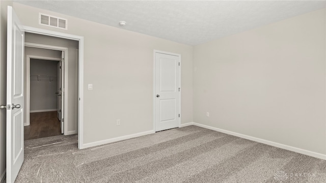 unfurnished bedroom featuring carpet, a textured ceiling, visible vents, and baseboards