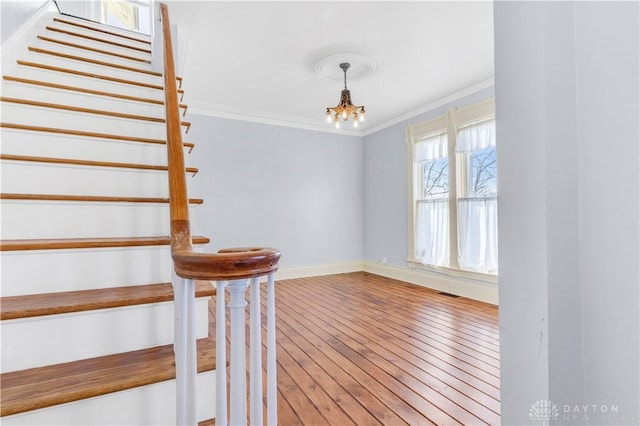 stairway featuring crown molding, hardwood / wood-style floors, and a notable chandelier