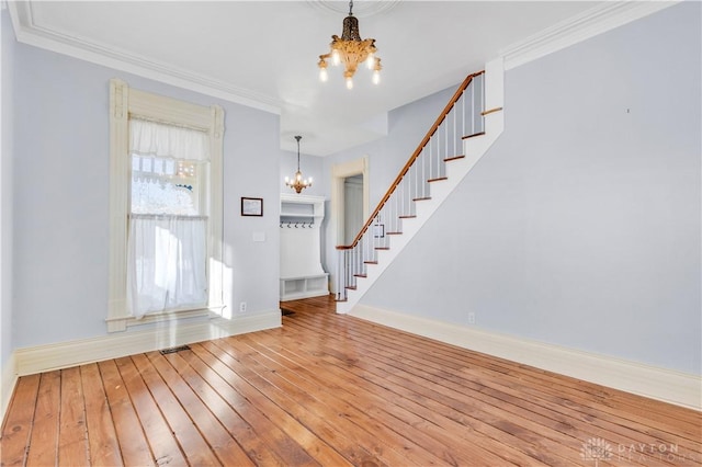 foyer with hardwood / wood-style floors, crown molding, and a chandelier