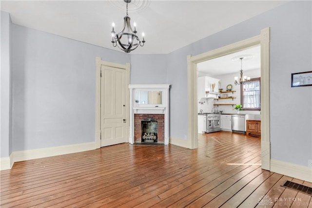 unfurnished living room with a fireplace, hardwood / wood-style floors, and a chandelier