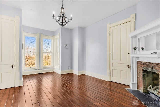 unfurnished dining area featuring a chandelier, a fireplace, and dark wood-type flooring