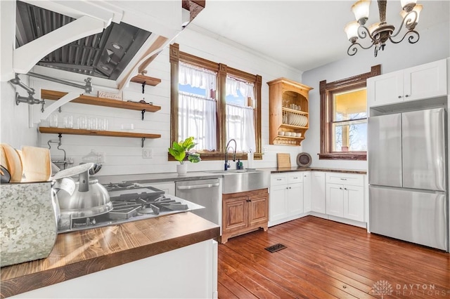 kitchen with white cabinets, stainless steel appliances, dark hardwood / wood-style floors, and a notable chandelier