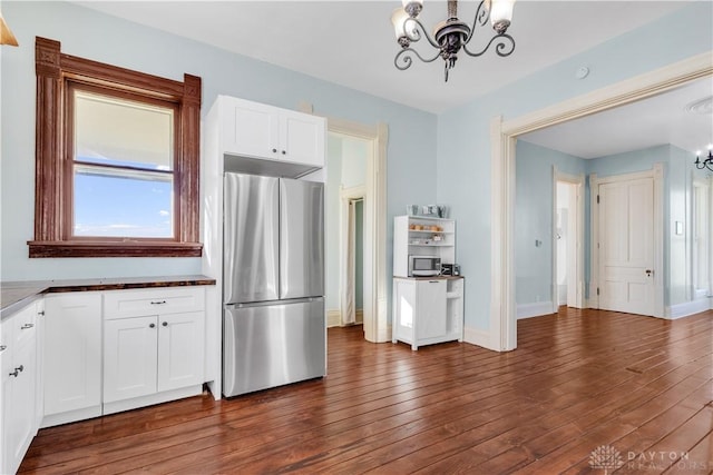 kitchen with stainless steel fridge, dark hardwood / wood-style flooring, white cabinetry, and a notable chandelier