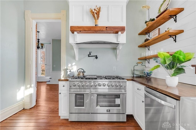 kitchen featuring appliances with stainless steel finishes, dark hardwood / wood-style flooring, butcher block countertops, and white cabinetry