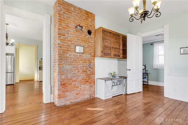 interior space featuring hardwood / wood-style flooring, a notable chandelier, and brick wall