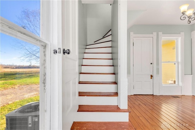 stairway featuring hardwood / wood-style floors and an inviting chandelier